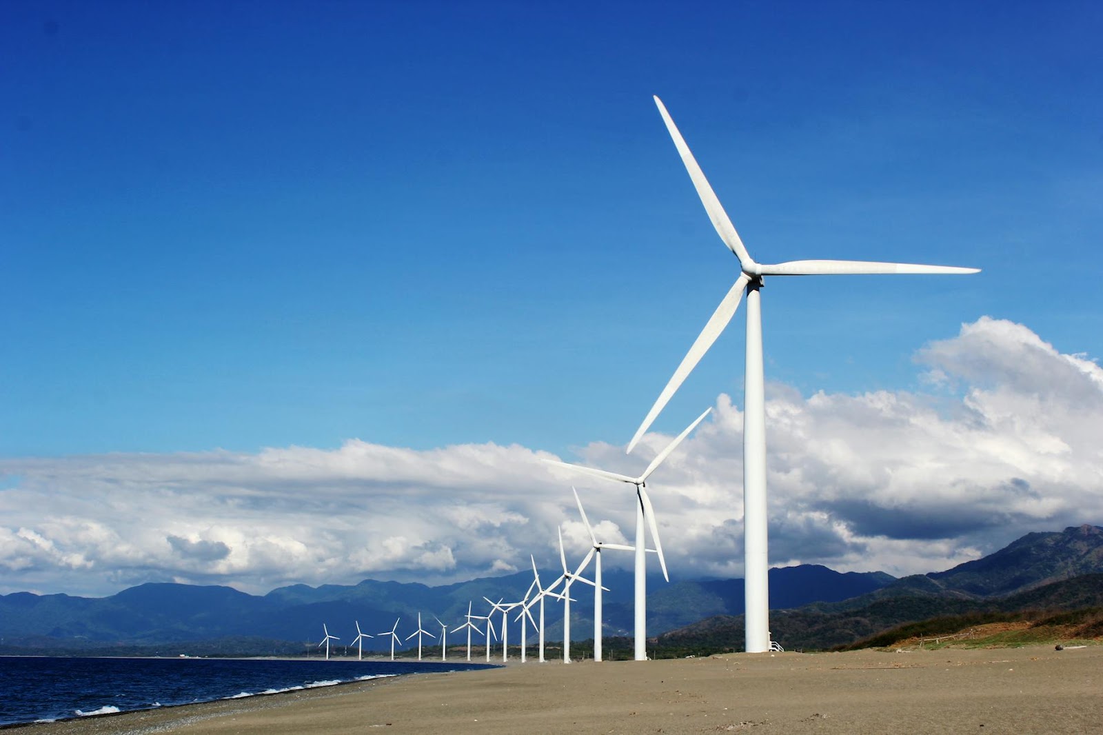 https://www.pexels.com/photo/white-wind-turbines-on-gray-sand-near-body-of-water-3976320/